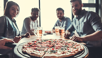 pizzeria patrons look as pizza is delivered to their table