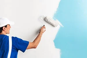 owner of a turnkey painting service business paints a wall
