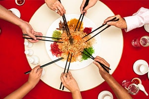patrons use chopsticks to eat from a plate of chinese food