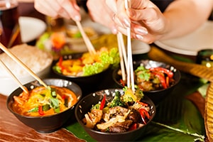 close up of hands of patrons enjoying food in a thai restaurant