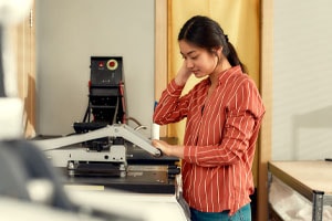 Employee using screen printer in screen printing store