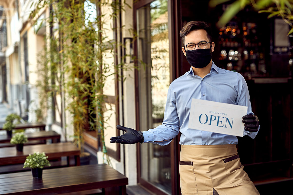 business owner wearing mask in front of storefront during covid-19