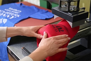 close up of worker printing on a hat in a screen printing business