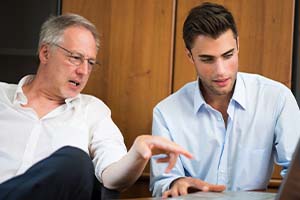 father showing son how to use programs in the family business